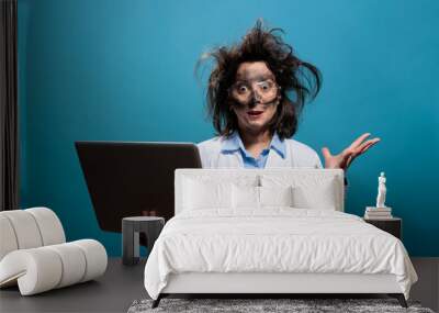 Lunatic chemist with messy hair and dirty face having laptop while gesticulating angrily after dangerous lab explosion. Insane scientist being enraged after failed laboratory chemical experiment. Wall mural