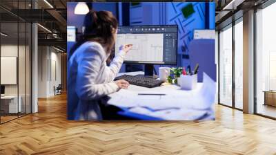 Over the shoulder shot of engineer woman drawing architectural plans and looking at cad software on desktop computer. Designer using arhitecture blueprints of buildings creating industrial prototype Wall mural