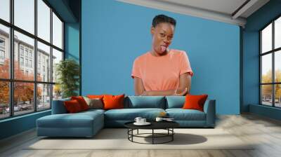 Playful woman sticking tongue out in front of camera. Foolish person doing crazy funny faces and expressions, making people smile and fooling around. Childish silly adult having fun Wall mural