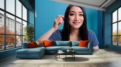 Portrait of asian influencer doing makeup tutorial in front of camera while recording content creator for vlogging channel. Vlogger woman using cosmetics brush advertising make up product Wall mural