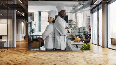 Portrait of chefs doing teamwork to cook food recipe in restaurant kitchen, sitting with arms crossed. Diverse team of cooks preparing to make culinary dish and gourmet meal with fresh ingredients. Wall mural