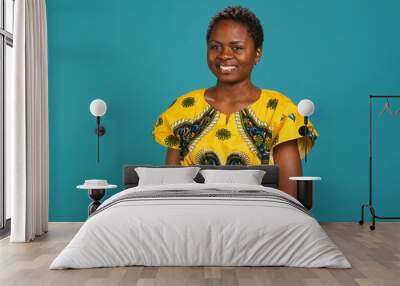 Portrait of natural smiling woman dressed in traditional ethnic clothes, posing in studio with a cute authentic laugh. Confident charming girl looking gorgeous in african culture attire. Camera A. Wall mural