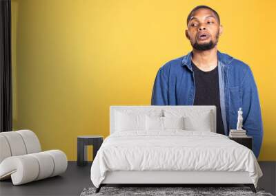 Portrait of relaxed cool african american person posing in studio, standing against yellow background in the studio. Confident athletic male model with a casual fashion style. Wall mural