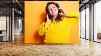 Portrait of smiling happy person dancing to music with modern headphones. Enthusiastic woman with a smile wearing a headset to listen to music and audio for entertainment. Wall mural