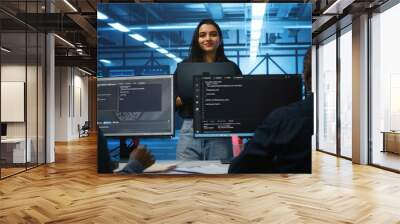 Portrait of smiling Indian manager in server room managing team of engineers looking for equipment misconfigurations. Happy team leader coordinating employees checking data center bottlenecks Wall mural