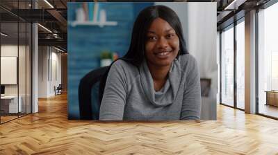 Portrait of student with black skin writing creative communication project for high school homework sitting at desk in living room. Teenager woman browsing graphic information on internet Wall mural