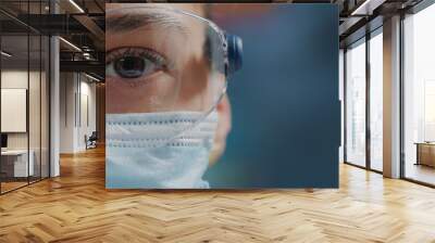 scientist showing one eye on camera in laboratory, wearing safety glasses and face mask. woman biolo Wall mural