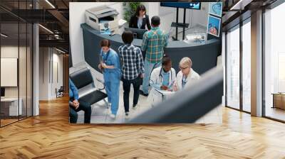 senior doctor and african american medic talking in hospital reception lobby, checking healthcare re Wall mural