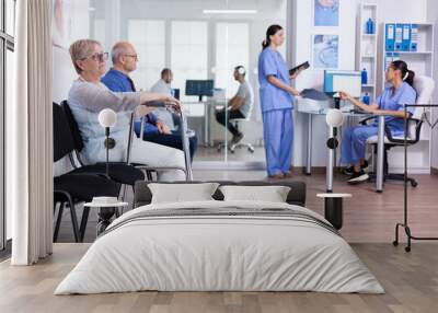 Senior woman with walking frame in hospital waiting room for rehabilitation treatment. Medical staff discussing about patient x-ray. Wall mural