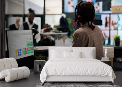 Showroom worker standing at cash register, checking boutique inventory report on computer in shopping centre. African american employee preparing packages with fashionable clothes for clients Wall mural