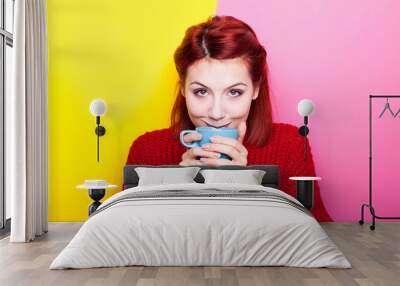 Smiing woman drinking her coffee on two colored background in yellow and pink Wall mural