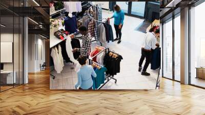 Top view of diverse customers checking stylish clothes, shopping for fashionable merchandise and accessories in modern boutique. Clients analyzing hangers with new fashion collection Wall mural