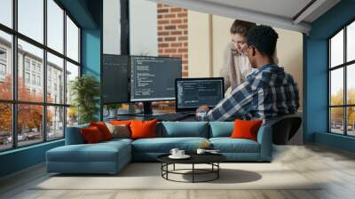 Two programmers doing high five hand gesture at desk with multiple screens running code celebrating successful algorithm. Software developers colleagues enjoying teamwork results in it agency Wall mural