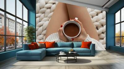 Horizontal view of hands holding cup of cacao on naked female legs  Wall mural