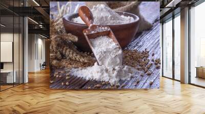 Shovel flour with wheat in background on wooden table Wall mural