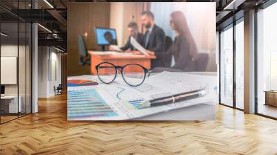 Business concept. Business people discussing, financial chart near 

dollars, focus on glasses on foreground Wall mural