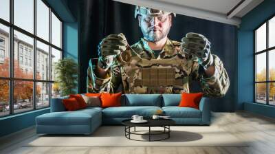 soldier in camouflaged uniform and tactical gloves holding military armored vest Wall mural