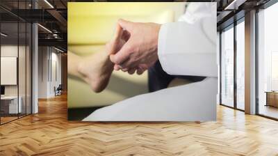 the hands of the doctor examines the foot of a patient Wall mural