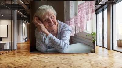 An elderly woman sitting in her home. Wall mural