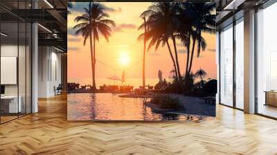 Beautiful sunset with palm trees silhouettes on a tropical beach. Wall mural