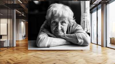 Close-up black and white portrait of a old woman at the table in home. Wall mural