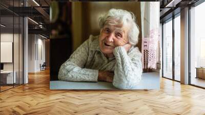 Portrait of elderly pensioner lady sitting at the table. Wall mural