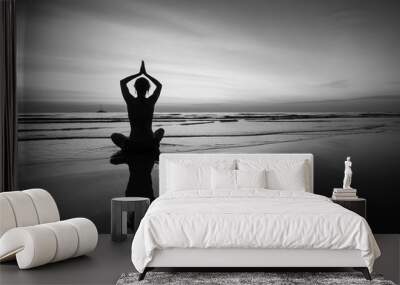 Woman doing meditation near the ocean beach. Black and white silhouette. Wall mural