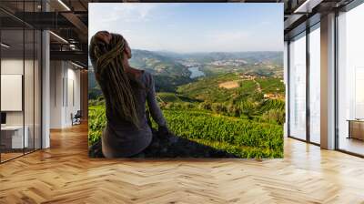 Woman with blond dreadlocks on the viewing point of Douro Valley, Portugal. Top view of river, and the vineyards are on a hills. Wall mural