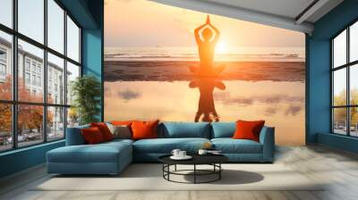 Yoga woman sitting in lotus pose on the beach during sunset. Wall mural