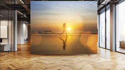 Young girl silhouette Jogging on sea beach . Wall mural