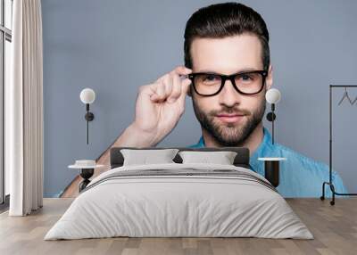 A portrait of young handsome man in jeans shirt  isolated on gray background touching his glasses Wall mural