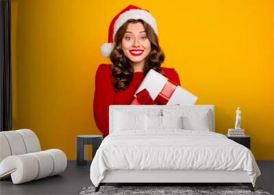 Beautiful lady holding large giftbox close to chest wear knitted jumper and santa hat isolated yellow background Wall mural