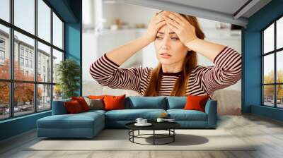 Close up photo beautiful she her lady arms hold head look side terrible suffer pain displeased grinning wear jeans denim striped pullover clothes bright comfort flat house living room indoors Wall mural