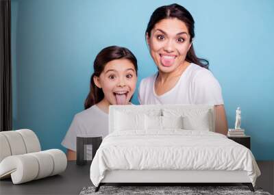 Close up photo beautiful two people brown haired mom little daughter friends hipsters silly mouth opened tongue out fooling around playing wear white t-shirts isolated bright blue background Wall mural