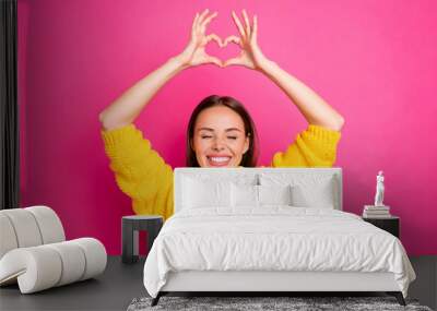 Close up photo of cheerful girl showing heart figure heart enjoying wearing yellow sweater isolated over fuchsia background Wall mural