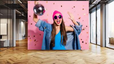 Close up photo of cheerful woman in eyeglasses eyewear holding mirror ball showing her palm wearing blue body suit isolated over pink background Wall mural