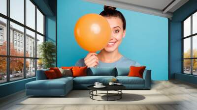 Close up photo of cute attractive lady hold hand orange ballons for anniversary hide feel content enjoy rejoice free time dressed cotton fashionable spring clothes isolated on blue background Wall mural