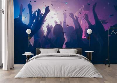 Close up photo of many party people dancing purple lights confetti flying everywhere nightclub event hands raised up wear shiny clothes Wall mural