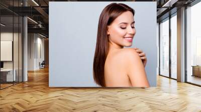 Close up portrait of beautiful amazing fresh young woman with toothy white smile, brown hair, she is looking down on her shoulder and touching it with a hand, isolated on grey background, copyspace Wall mural