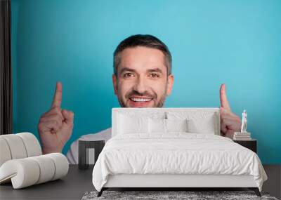 Close-up portrait of his he nice attractive content cheerful cheery bearded guy wearing tshirt pointing two forefingers up copy space isolated over bright vivid shine vibrant blue color background Wall mural