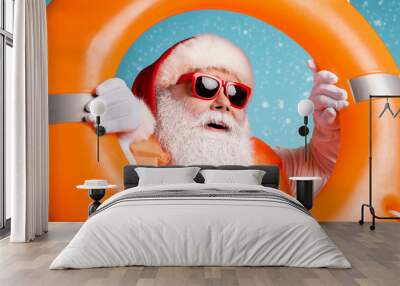 Close-up portrait of his he nice cheerful glad dreamy white-haired Santa swimmer looking through orange ring resort rest exotic tour isolated bright vivid shine vibrant blue color background Wall mural