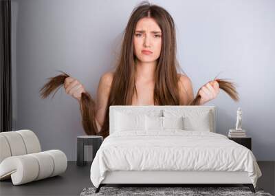 Close-up portrait of nice attractive pretty depressed sad unwell unhealthy brown-haired girl holding in hand dry ends remedy lotion conditioner solution isolated on light gray pastel color background Wall mural