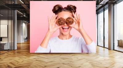 Close-up portrait of nice lovely attractive cheerful cheery girl holding in hands two cakes closing covering eyes opened mouth isolated over pink pastel background Wall mural