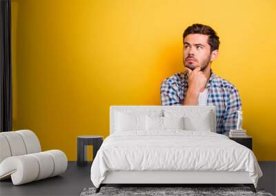 Close up portrait of thoughtful man who looks away touching his chin and weighs the pluses and minuses of the offer isolated on bright yellow background with copy space for text Wall mural