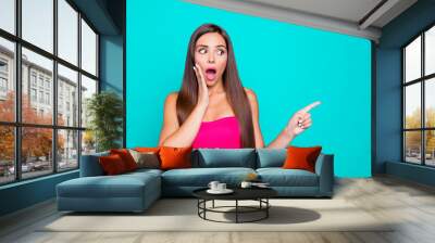 Close up studio photo portrait of amazed shocked surprised scared terrified with open mouth lady pointer showing on copy space holding hand near mouth isolated bright background Wall mural