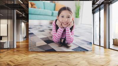 Closeup photo of young charming toothy smiling kid little brunette girl laying floor carpet at home touch cheeks dreamy isolated in her room Wall mural