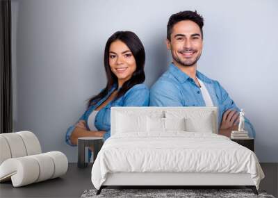 Concept of multiethnic cooperation and friendship. Attractive delightful hispanic woman in denim clothes and handsome causasian smiling man in jeans shirt are standing back to back against  background Wall mural