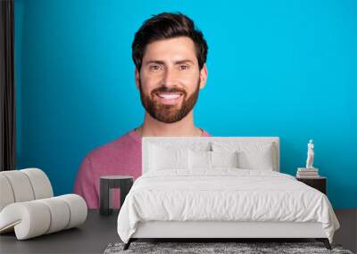 Confident young man in casual attire smiling against a solid blue backdrop exemplifying modern style and charisma in a colorful setting Wall mural