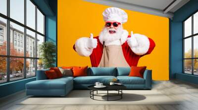 Crazy santa claus with beard in chef headwear cook show thumb up sign x-mas christmas holly jolly feast cooking wear apron sunglass isolated bright shine color background Wall mural