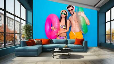 Delight pleasure leisure daydream concept. Portrait of funky positive couple with colorful rubber rings enjoying rest isolated on bright blue background Wall mural